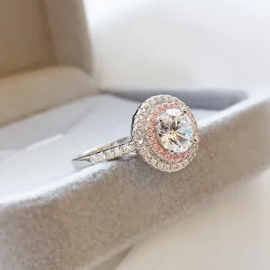 Close-up detail shot of a sparkling double halo pink diamond ring in a velvet box.