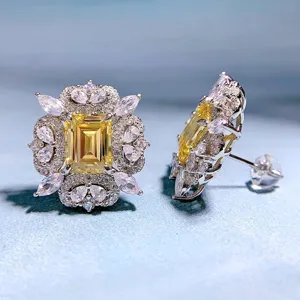 Exquisite Ohrstecker mit gelbem Zirkonia im Smaragdschliff und funkelnden Zirkoniasteinen Detail.