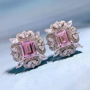 Nahaufnahme von luxuriösen rosa Ohrringen mit smaragdschliff Stein und Kristallen.