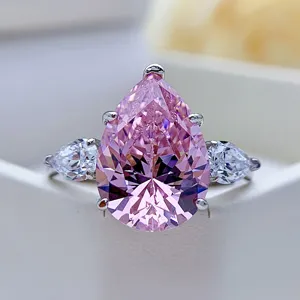 Exquisito anillo de compromiso con gema rosa en forma de pera y piedras laterales de plata.