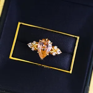 Close-up detail shot of the elegant pear-cut padparadscha ring with sparkling side stones.