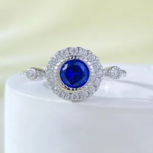 Primo piano dettagliato di un elegante anello in argento con pietra centrale blu lucida.