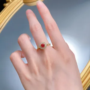 Elegante anello in argento S925 bagnato d'oro con pietra rossa rotonda da 5,0 mm e alone di zircone.