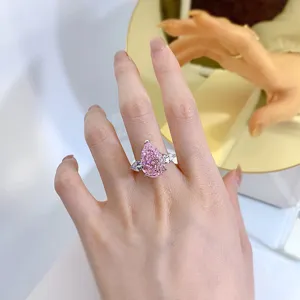 Detalle de cerca del impresionante anillo de diamante rosa en forma de pera con piedras laterales.