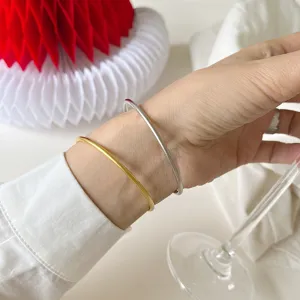 Nahaufnahme von minimalistischen dünnen Gold- und Silber-Offenarmreifen am Handgelenk.