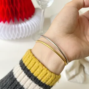 Nahaufnahme Detailansicht minimalistischer zweifarbiger Gold- und Silber-Armreifen am Handgelenk.