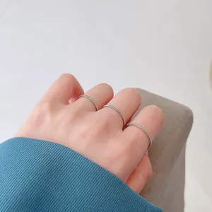 Nahaufnahme minimalistischer gestapelter dünner Silberringe an der Hand, eleganter Stil.