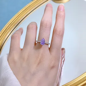 Dettaglio in primo piano di un anello in argento con pietra viola a pera e piccoli zirconi.