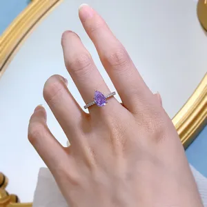 Primo piano di un anello con gemma viola taglio a pera e delicato dettaglio in argento.
