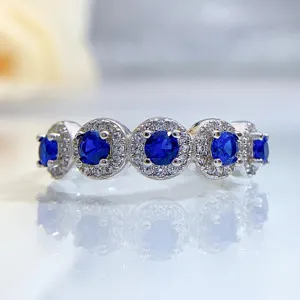 Exquisite silver ring detail featuring sparkling blue stones and pavé halo diamonds for elegance.