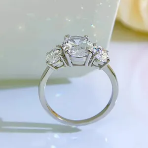 Primer plano detallado de un anillo de tres piedras ovaladas brillante con montura de plata.