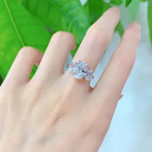 Detalle en primer plano de un anillo de compromiso de tres piedras con una brillante piedra ovalada.