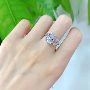 Primer plano detalle de un elegante anillo ovalado con tres piedras en la mano brillante.