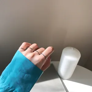 Nahaufnahme Detailansicht minimalistischer silberner Ringe an der Hand mit gemütlichem Kerzenlicht.