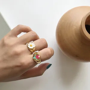 Nahaufnahme von bunten Emaille Blumen Siegelringen an der Hand, stilvoll und fein.
