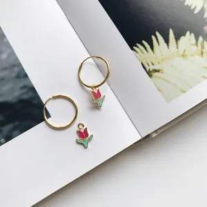 Schicke goldene Creolen mit lebendigen rosa-grünen Emaille-Tulpen-Anhängern, Detailansicht.