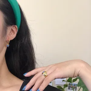 Goldfarbene Schmetterling-Creolen und eleganter Statement-Ring mit blauem Emailleschmuck.