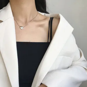 Detailansicht einer filigranen silbernen Meteorit Anhänger Kette zum weißen Blazer.