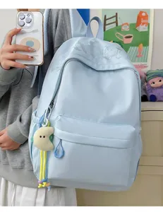 Detail view of a light blue minimalist backpack with cute charm and spacious compartments.