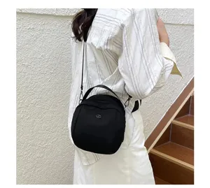 Detailed view of the stylish black crossbody shell bag worn by the model on stairs.
