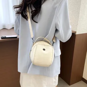 Minimalist beige nylon shell crossbody bag, versatile everyday shoulder handbag with top handle.