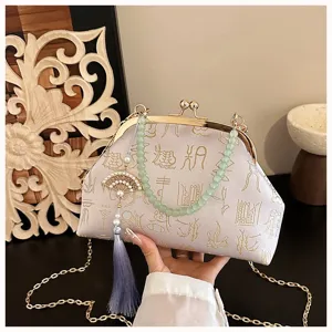 Close-up of Chinese style jacquard evening bag detail, featuring beaded handle and tassel pendant.