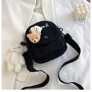 Cute canvas crossbody bag with plush bear charms and front pocket for daily use.