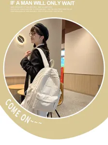 Detailed lifestyle view of a minimalist white casual backpack with front pocket and shoulder straps.