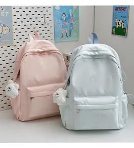 Detailed view of the cute student backpack with bow embroidery and plush pendant in pastel tones.