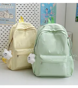 Cute bow embroidered student backpack detail showing pastel yellow and green casual school bags.