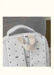 Primo piano dei dettagli dello zaino bianco con pois neri e graziosa stampa a fiocco.