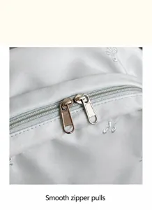 Close up view of the backpack zipper and smooth metal puller with cute embroidered bow details.