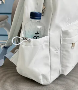 Backpack side pocket detail showing convenient storage for water bottles with cute bow embroidery.