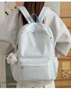Light blue student backpack detail, cute bow embroidery pattern and lovely plush pendant view.