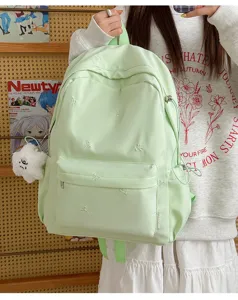 Close up of light green student backpack with cute bow embroidery, casual school bag detail view.