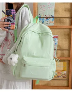 Light green school backpack with cute bow embroidery and plush pendant for daily use.
