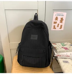 Detail view of a minimalist black school backpack, lightweight travel daypack for students.