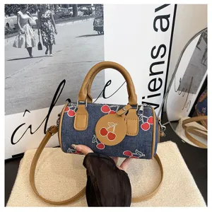 Chic denim cherry print cylindrical shoulder bag with brown leather handles for daily use.