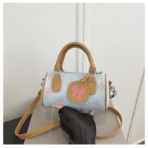 Chic denim pillow bag with brown trim and pink bow print, stylish casual crossbody handbag.