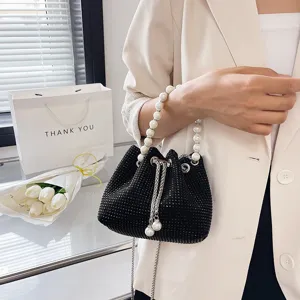 Black rhinestone bucket bag detail shot with pearl handle and chic chain drawstring.