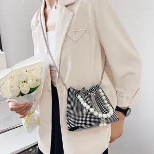 Detailed shot of a black rhinestone bucket bag with pearl handle and chain strap.