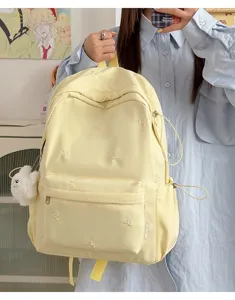 Sweet style pale yellow school backpack with cute embroidered bows and plush pendant for daily use.
