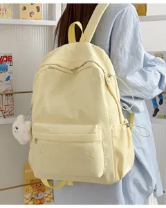 Light yellow student backpack detail with cute bow embroidery and fluffy plush charm.