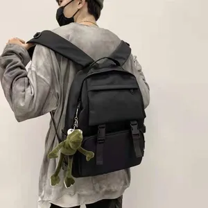 Black tactical backpack with cute frog pendant, casual travel school bag for daily use.