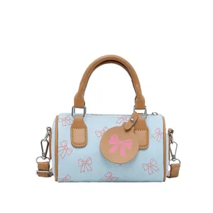 Chic casual blue barrel pillow bag with cute pink bow print and brown leather trim handles.