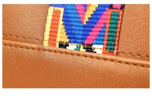Close-up detail of women handbag featuring premium brown PU leather and colorful boho woven strap.