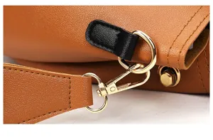 Close-up detail of women's handbag strap buckle, gold metal hardware and brown leather texture.