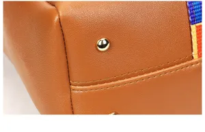 Detailed view of women's handbag bottom with protective metal feet and colorful strap.