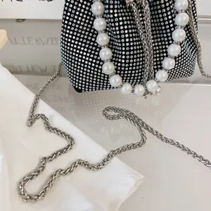 Black rhinestone bucket bag detail with pearl handle and metal chain strap, luxury style.