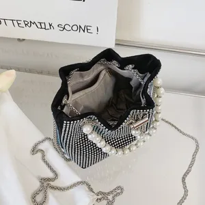 Detailed view of a black rhinestone bucket bag with pearl handle and silver chain strap.